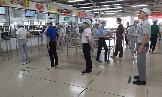 Người lao động Công ty Nidec Việt Nam xếp hàng chờ lấy suất ăn ca vẫn phải giữ khoảng cách an toàn 2m. Ảnh: Lưu Kim Hồng