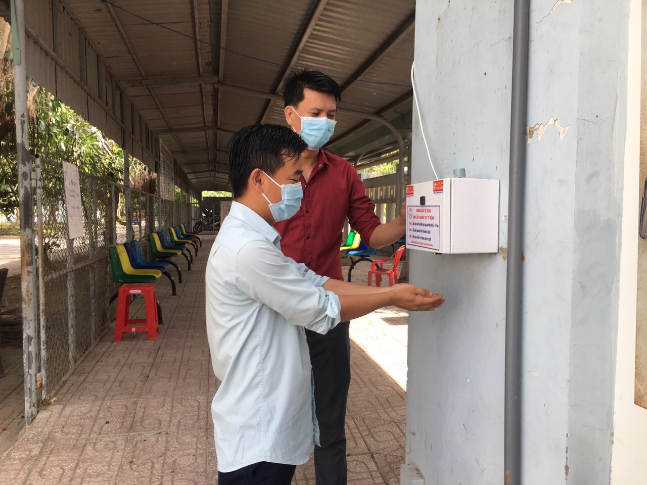 Anh Nguyễn Duy Phong (áo đỏ) đang hướng dẫn bệnh nhân sử dụng máy sát khuẩn tự động do anh sáng chế. Ảnh: Thiên Lý