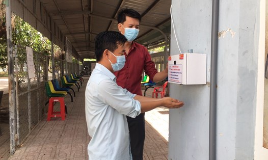 Anh Nguyễn Duy Phong (áo đỏ) đang hướng dẫn bệnh nhân sử dụng máy sát khuẩn tự động do anh sáng chế. Ảnh: Thiên Lý