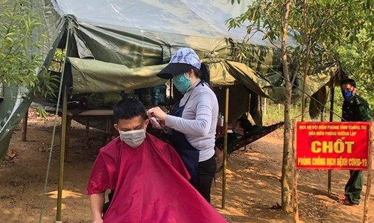 Chị Dung, vợ của thiếu tá Võ Văn Lĩnh hỗ trợ cắt tóc cho cán bộ, chiến sĩ, dân quân và công an viên ở các chốt phòng dịch COVID-19. Ảnh: Phan Vĩnh.