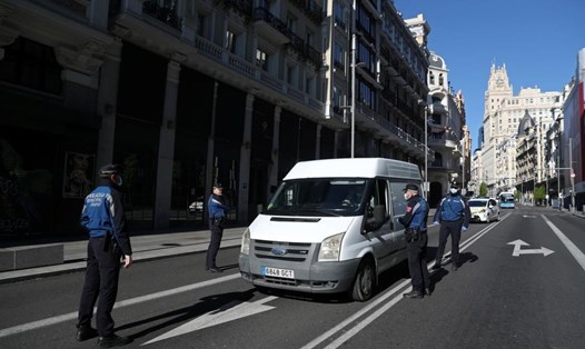 Các sĩ quan cảnh sát đeo mặt nạ kiểm tra một chiếc xe trên đường Gran Via ở Madrid, Tây Ban Nha, ngày 4.4. Ảnh: Reuters