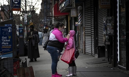 Một phụ nữ đeo khẩu trang cho trẻ ở New York, Mỹ. Ảnh: AP.