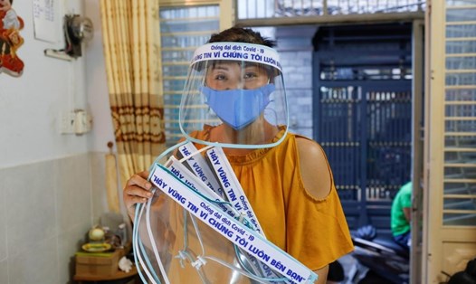 Chị Quách Mỹ Linh, tiểu thương ở chợ Bà Chiểu, cùng các tấm che mặt tự chế để ủng hộ các nhân viên y tế trên tuyến đầu chống dịch COVID-19 ở Việt Nam. Ảnh: Reuters