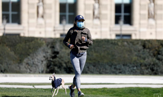 Một người dân đeo khẩu trang đang chạy bộ cùng con chó trong vườn Tuileries, Paris, Pháp trong thời gian phong tỏa vì đại dịch COVID-19. Ảnh: Reuters