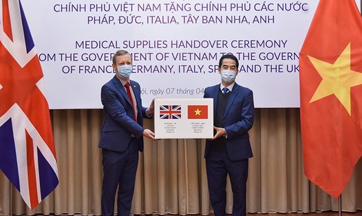 Thứ trưởng Tô Anh Dũng trao tặng vật tư y tế cho Đại sứ Anh. Ảnh: BNG