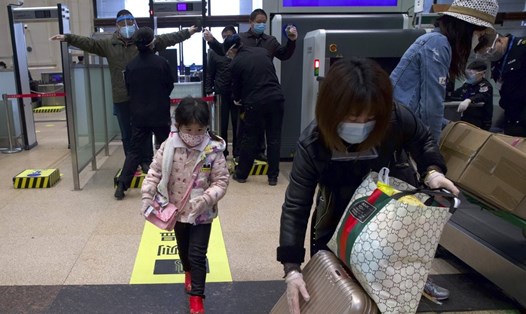 Hành khách đeo khẩu trang kiểm tra an ninh tại nhà ga Hankou sau khi hoạt động đường sắt nối lại ở Vũ Hán ngày 8.4. Ảnh: AP.