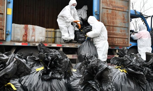 Nhân viên làm công việc thu dọn rác mặc đồ bảo hộ để tránh tiếp xúc trực tiếp với rác thải y tế. Ảnh: Reuters.