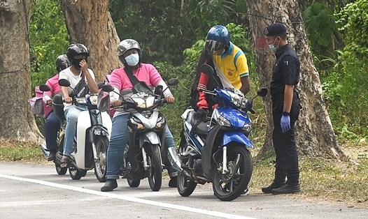 Một cảnh sát đang kiểm tra những người di chuyển bằng xe máy tại Penang, Malaysia hôm 22.4. Ảnh: AFP.