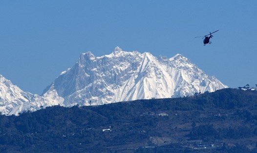Trực thăng cứu hộ bay ở phía trước dãy núi Annapurna, Nepal tìm thi thể thành viên đoàn leo núi hôm 22.1 sau trận lở tuyết. Ảnh: AFP.