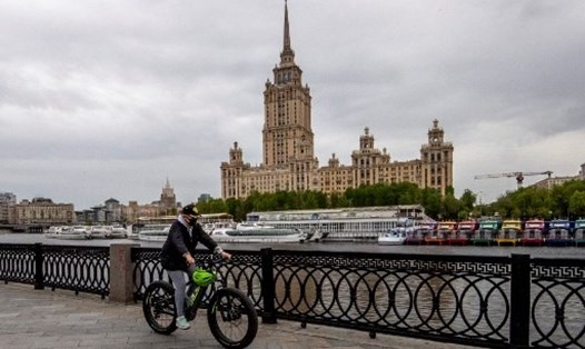 Một phụ nữ đạp xe bên bờ sông Moskva ở trung tâm Mátxcơva, Nga, ngày 10.5. Ảnh: AFP