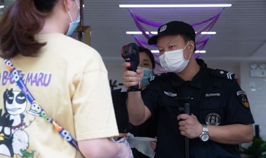 Nhân viên bảo vệ kiểm tra nhiệt độ cho một phụ nữ ở Vũ Hán hôm 11.5. Ảnh: AFP.
