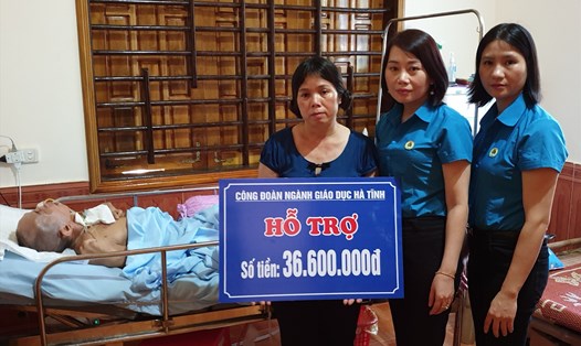 Bà Nguyễn Thị Nhung Quyên - Chủ tịch Công đoàn Giáo dục Hà Tĩnh (giữa) trao tiền hỗ trợ cho vợ thầy Mão để giúp đỡ thầy bị tai nạn nằm liệt giường. Ảnh: CĐ