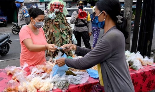 Cảnh sát ở Bali đang tuyên truyền cho người dân về phòng chống COVID-19 tại một khu chợ ở Kerobokan, gần Denpasar. Ảnh: AFP.