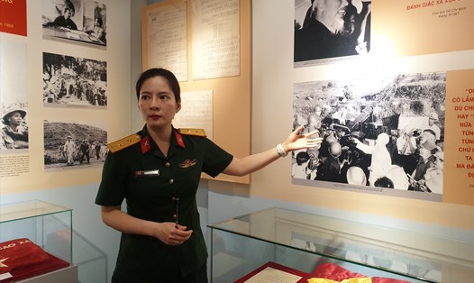 Hướng dẫn viên giới thiệu về hình ảnh Bác Hồ thăm trận địa pháo, động viên các chiến sĩ bảo vệ bầu trời miền Bắc trong kháng chiến chống Mỹ. Ảnh: Phạm Đông