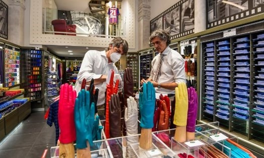 Nhân viên cửa hàng sắp xếp các mặt hàng áo sơ mi và cà vạt để mở cửa trở lại ở khu thời trang của Milan. Ảnh: AFP
