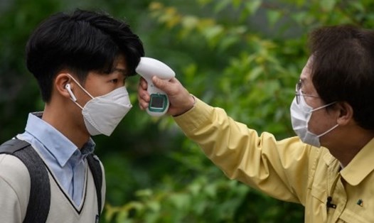 Học sinh đeo khẩu trang và phải kiểm tra thân nhiệt trước khi vào lớp học tại một trường cấp 3 ở Hàn Quốc. Ảnh: AFP