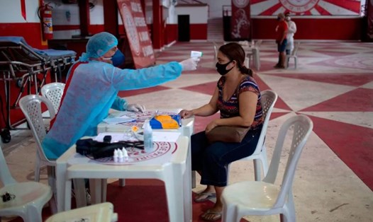 Bác sĩ kiểm tra nhiệt độ cho người có triệu chứng COVID-19 tại một trường học ở Rio de Janeiro, Brazil hôm 24.5. Ảnh: AFP.