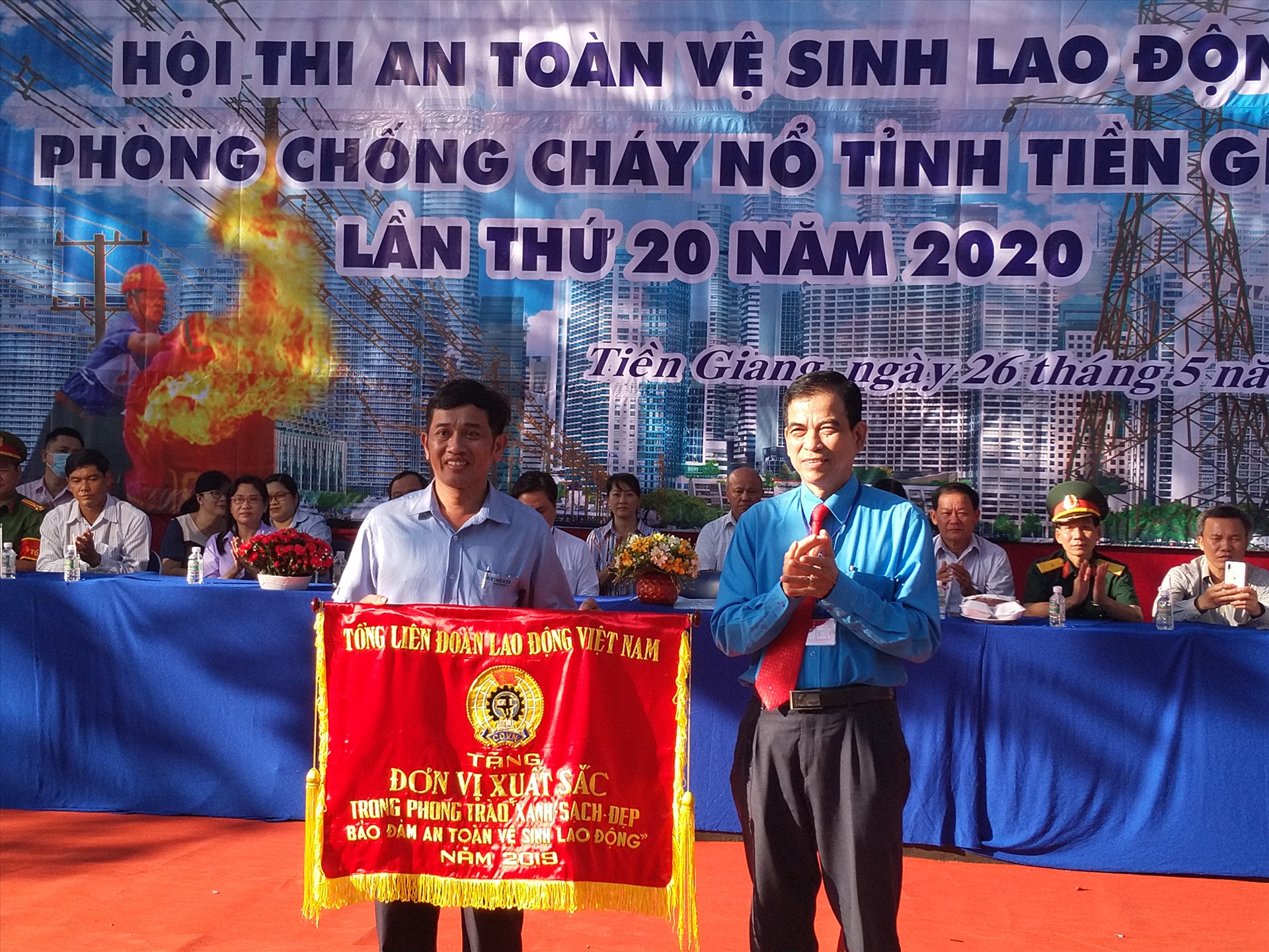 Chủ tịch LĐLĐ tỉnh Tiền Giang - ông Trương Văn Hiền - trao Cờ của Tổng LĐLĐVN tặng đơn vị xuất sắc thực hiện an toàn, vệ sinh lao động tỉnh Tiền Giang. Ảnh: K.Q