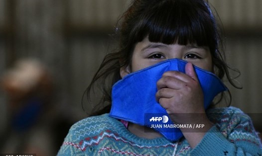 Một bé gái dùng khẩu trang trong dịch COVID-19 để tránh lây lan virus. Ảnh: AFP