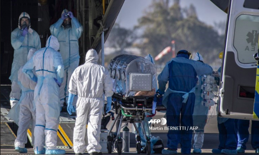 Bệnh nhân COVID-19 đang được đưa lên máy bay để chuyển từ thành phố Santiago sang thành phố Concepcion ở Chile, để giảm tải cho hệ thống y tế. Ảnh: AFP