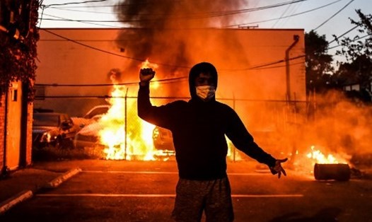 Người biểu tình cạnh những chiếc xe bị đốt cháy trong một cuộc biểu tình ở thành phố Minneapolis, bang Minnesota, Mỹ, sau cái chết của George Floyd. Ảnh: AFP.