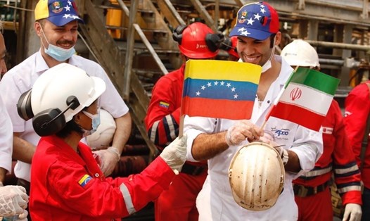 Công nhân cầm cờ Venezuela và Iran chào đón tàu chở dầu của Iran. Ảnh: EPA
