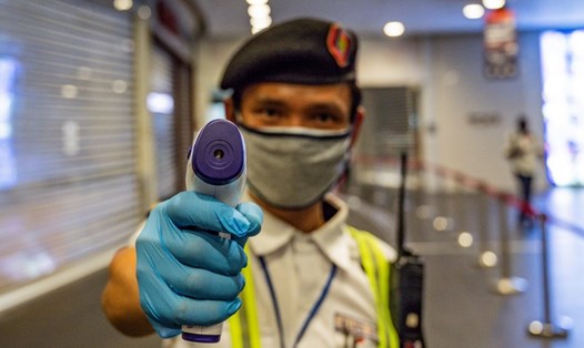 Một nhân viên bảo vệ kiểm tra nhiệt độ khách hàng trước khi vào trung tâm mua sắm ở Kuala Lumpur, Malaysia hôm 4.5. Ảnh: AFP.