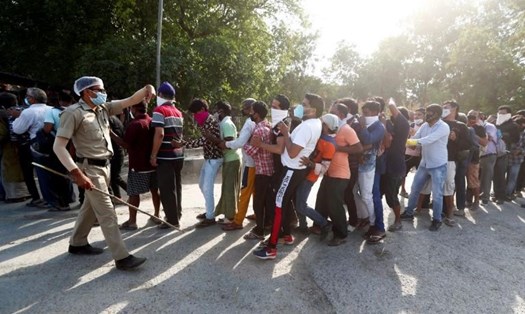Một cảnh sát cố gắng kiểm soát đám đông bên ngoài một cửa hàng rượu ở New Delhi, Ấn Độ hôm 4.5. Ảnh: Reuters.