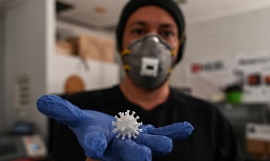 Nhân viên phòng thí nghiệm cùng mô hình in 3D của virus SARS-CoV-2 tại Athens, Hy Lạp. Ảnh: AFP