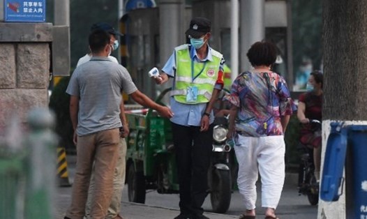 Nhân viên đo nhiệt độ cho người dân trên đường phố bên ngoài chợ Xinfadi ở Bắc Kinh hôm 12.6. Chợ bán buôn Xinfadi và chợ hải sản Jingshen đã bị đóng cửa để khử trùng sau khi các ca COVID-19 mới ở Bắc Kinh được xác nhận đã tới những chợ này. Ảnh: AFP.