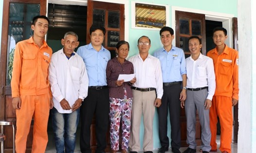 Ông Nguyễn Thành Long (thứ 2 từ trái) và vợ (thứ 4) trong ngày nhận nhà mới. Ảnh: PC Quảng Nam.