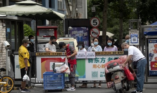 Người dân đeo khẩu trang chờ giao hàng đặt trực tuyến tại một khu dân cư gần chợ Tân Phát Địa. Ảnh: AFP.
