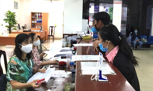 Cán bộ Bảo hiểm xã hội TPHCM hướng dẫn người dân thực hiện đổi thẻ bảo hiểm y tế. Ảnh: Lam Sơn