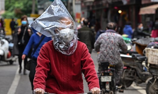 Một người đàn ông đeo khẩu trang, trùm túi nilon lên đầu đạp xe trên đường phố Vũ Hán, tỉnh Hồ Bắc, Trung Quốc. Ảnh: AFP.