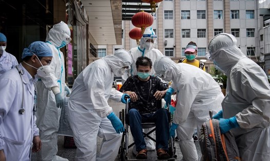 Nhân viên y tế Trung Quốc đỡ một bệnh nhân COVID-19 hồi phục xuất viện. Ảnh: AFP.
