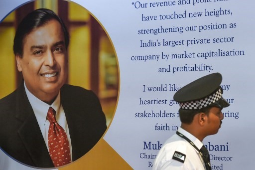 Một nhân viên bảo vệ đang đi qua poster có in chân dung Mukesh Ambani - người giàu nhất Ấn Độ và chủ tịch tập đoàn dầu khí viễn thông Reliance Industries ở Mumbai tháng 12.2019. Ảnh: AFP.