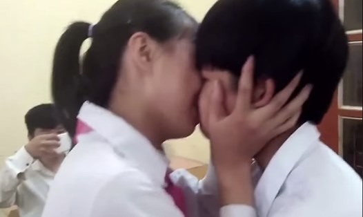 Hai học sinh với khuôn mặt còn non choẹt, vai đeo khăn quàng đỏ, hôn nhau công khai trên lớp. Ảnh cắt từ clip