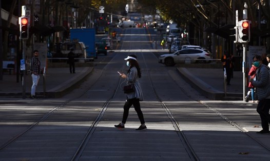 Một người phụ nữ băng qua đường trong khu trung tâm của Melbourne. Ảnh: AFP.