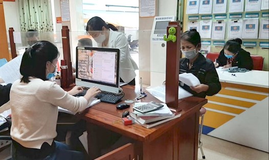 Cán bộ BHXH tỉnh Hà Tĩnh hướng dẫn người lao động tự do hoàn thiện hồ sơ tham gia BHXH tự nguyện. Ảnh: BHXHHT