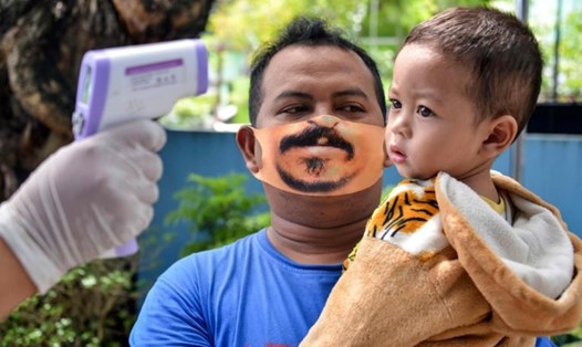 Một ông bố đeo khẩu trang thiết kế bằng cao su tổng hợp đang rất thịnh hành ở Indonesia. Ảnh: AFP