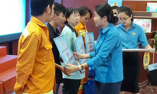Bà Trương Thị Minh Dung, Chủ tịch LĐLĐ Quận 1, trao 4 sổ tiết kiệm (5 triệu đồng/sổ) cho các CNLĐ bị tai nạn lao động. Ảnh Nam Dương