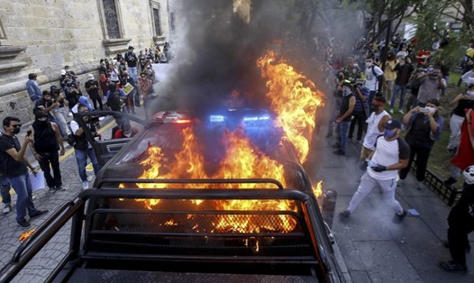 Người biểu tình đốt xe cảnh sát hôm 4.6 tại Mexico. Ảnh: AFP.