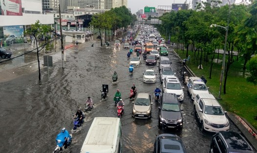 Hàng ngàn người dân TPHCM vất vả lội nước trên đường Nguyễn Hữu Cảnh trong cơn mưa chiều 3.6.   Ảnh: Minh Quân