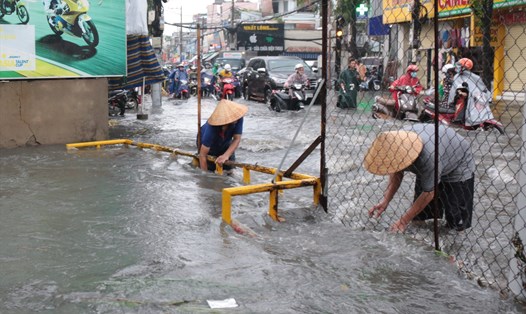 Người dân trên đường Tô Ngọc Vân (Quận Thủ Đức) phải vớt rác ở kênh cho nước thoát nhanh mỗi khi mưa lớn.  Ảnh: Minh Quân