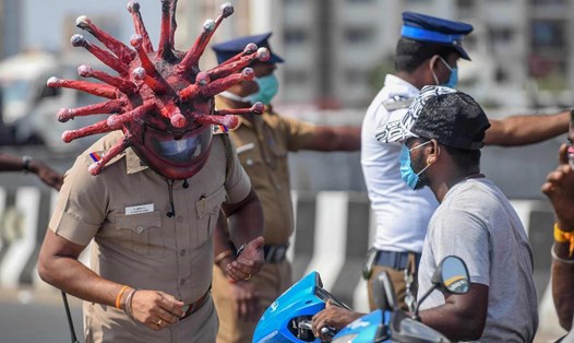 Cảnh sát Ấn Độ đội mũ bảo hiểm thiết kế theo hình dạng virus SARS-CoV-2 đang trao đổi với người dân ở một trạm kiểm soát thực thi lệnh phong tỏa chống COVID-19. Ảnh: AFP.