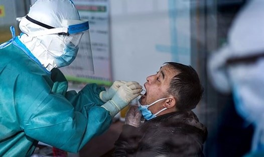 Nhân viên y tế lấy mẫu xét nghiệm COVID-19 của người dân. Ảnh: AFP