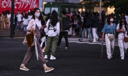 Người dân đeo khẩu trang đi qua đường ở Tokyo. Thủ đô Nhật Bản đang trong tình trạng cảnh báo COVID-19 cao nhất sau khi số ca tăng đột biến. Ảnh: AFP.