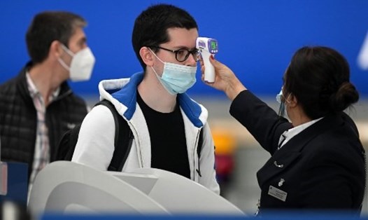 Nhân viên sân bay kiểm tra nhiệt độ của một hành khách đeo khẩu trang trong đại dịch COVID-19. Ảnh: AFP