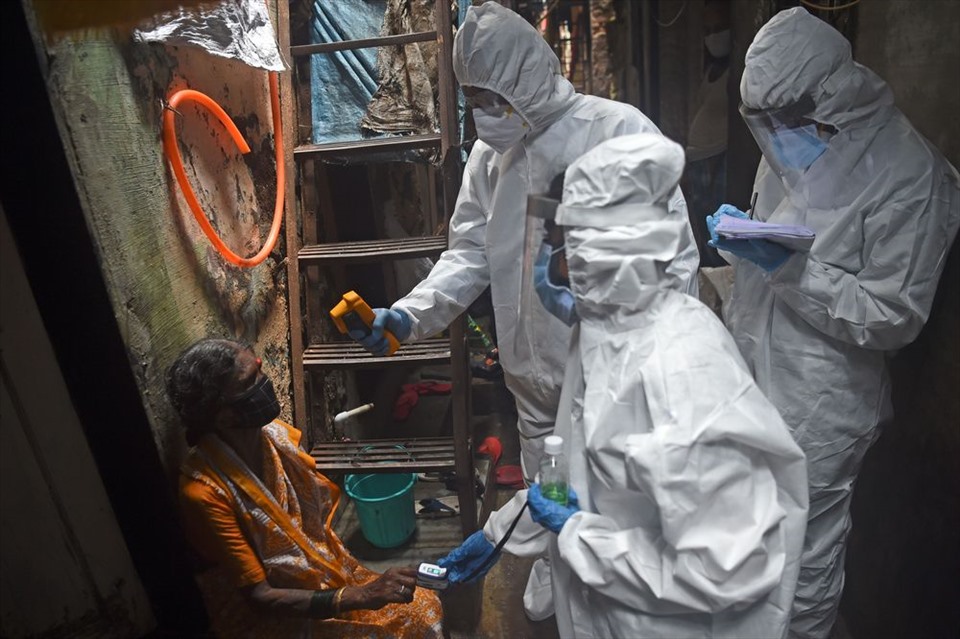 Nhân viên y tế đo nhiệt độ cho một phụ nữ trong khu ổ chuột Dharavi ở Mumbai. Ảnh: AFP.