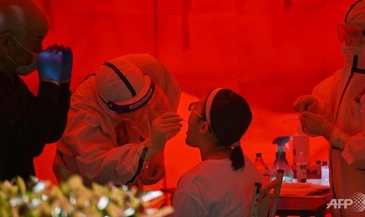 Nhân viên y tế lấy mẫu phết họng một phụ nữ để xét nghiệm COVID-19 ở Vũ Hán, tỉnh Hồ Bắc, Trung Quốc. Ảnh: AFP.